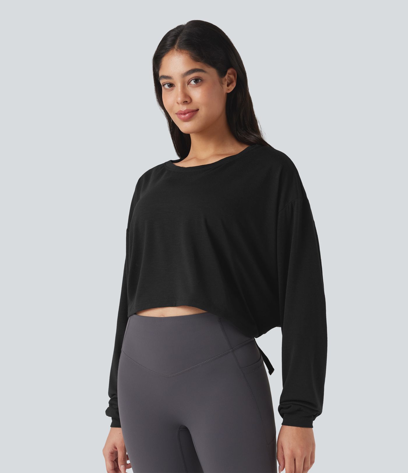 Top deportivo para correr de cuello redondo, manga larga, con aberturas y lazo en la espalda.