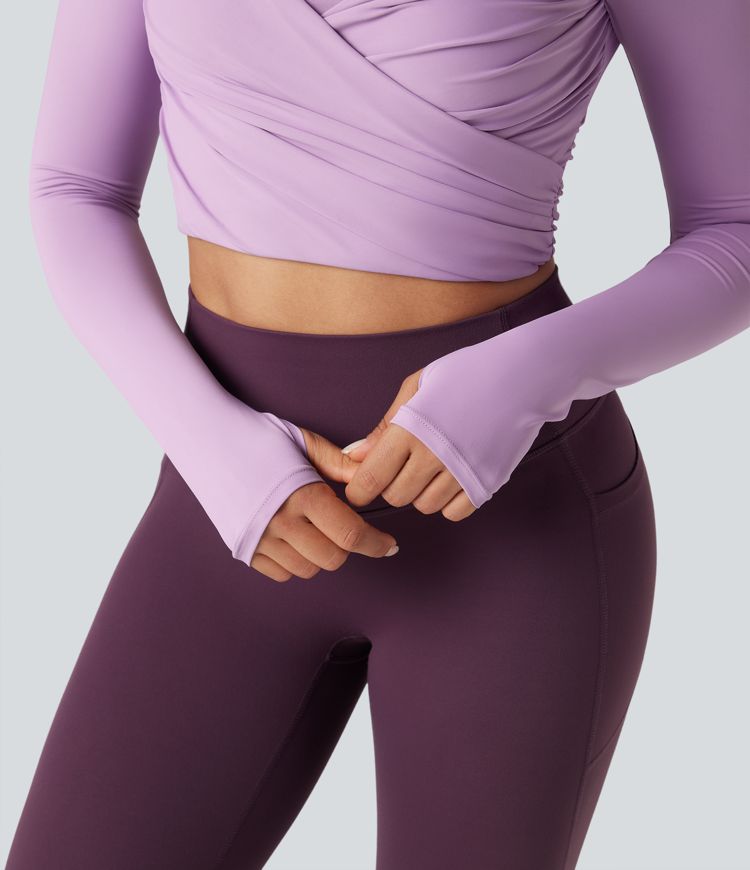 Trumpintas jogos sportinis topas su push-up efektu, formuotais spacer kaušeliais, apvalia iškirpte, ilgomis rankovėmis su nykščių angomis ir kryžminiu dizainu.