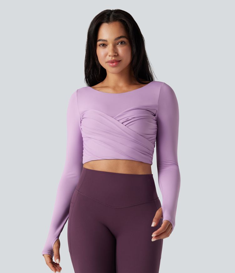 Trumpintas jogos sportinis topas su push-up efektu, formuotais spacer kaušeliais, apvalia iškirpte, ilgomis rankovėmis su nykščių angomis ir kryžminiu dizainu.