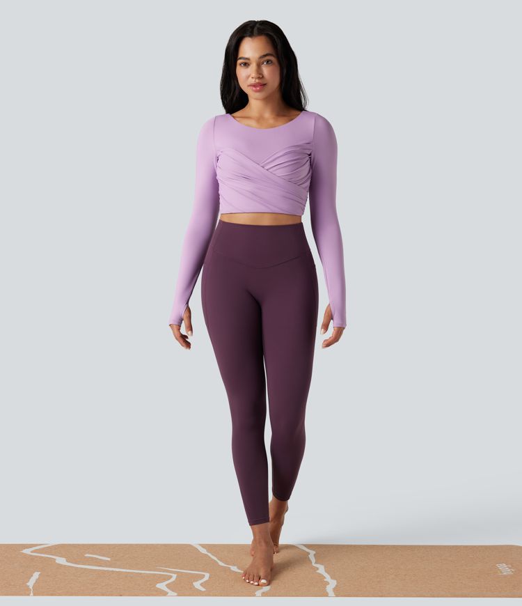 Trumpintas jogos sportinis topas su push-up efektu, formuotais spacer kaušeliais, apvalia iškirpte, ilgomis rankovėmis su nykščių angomis ir kryžminiu dizainu.