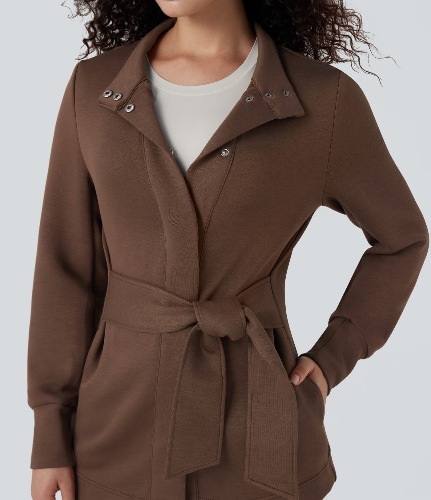 Högkragad långärmad arbetsrock med knytband och fickor.