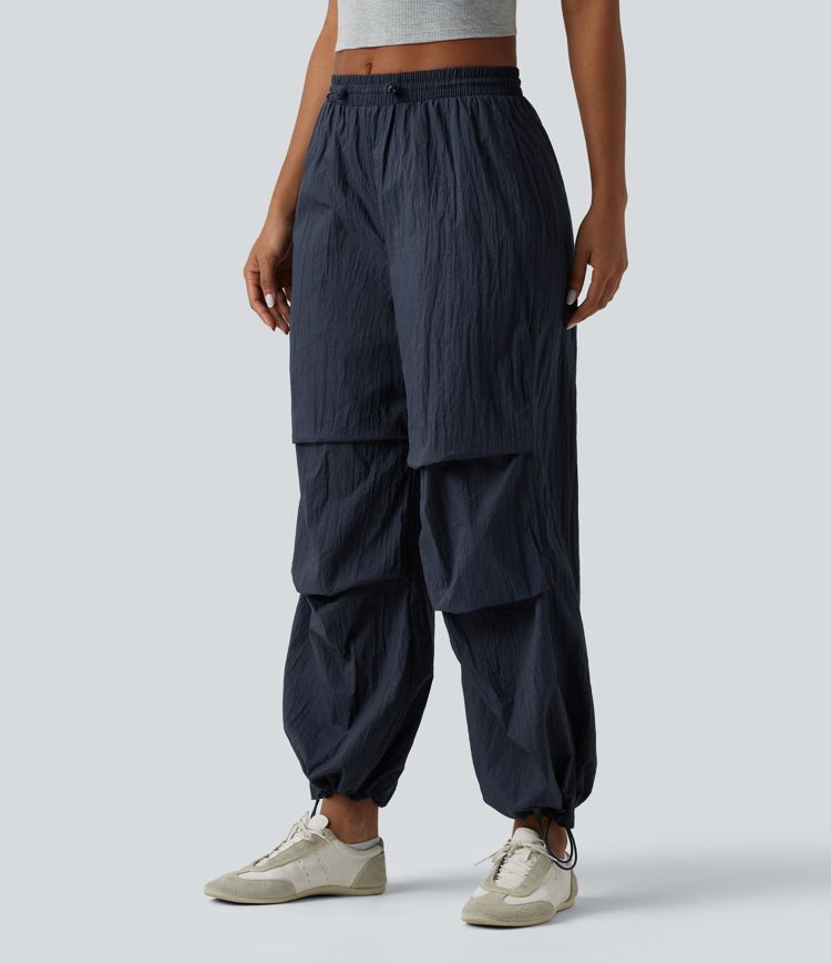 Pantaloni jogger casual tip parașută, ușor, durabili și hidrofugi, cu talie medie, croială dreaptă și buzunare.