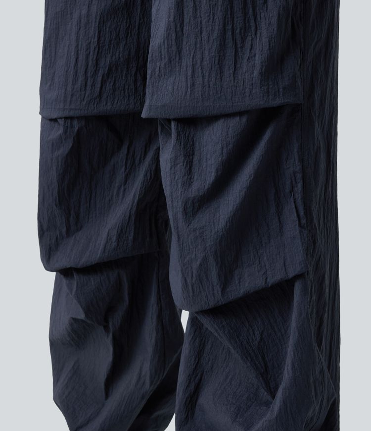 Pantaloni jogger casual tip parașută, ușor, durabili și hidrofugi, cu talie medie, croială dreaptă și buzunare.