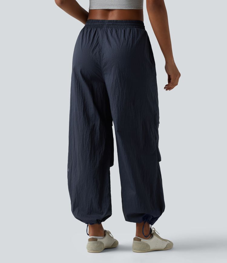 Pantaloni jogger casual tip parașută, ușor, durabili și hidrofugi, cu talie medie, croială dreaptă și buzunare.