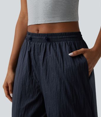 Pantaloni jogger casual tip parașută, ușor, durabili și hidrofugi, cu talie medie, croială dreaptă și buzunare.