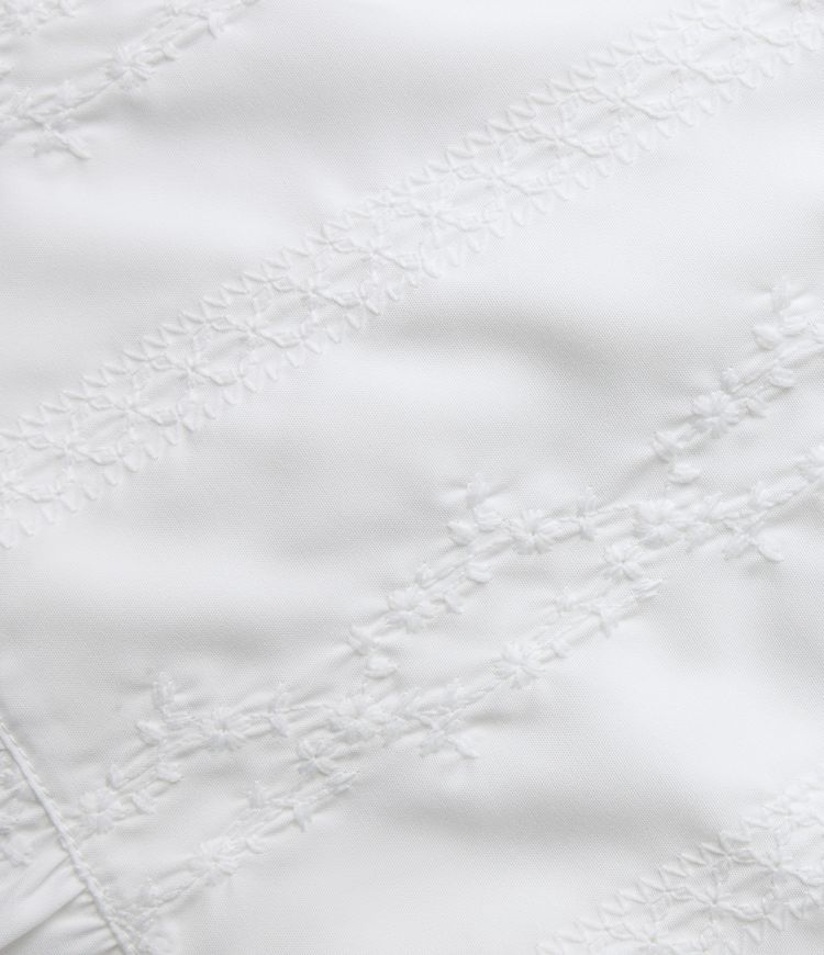 Top sin mangas estilo resort con escote en V, bordado y bajo con volante