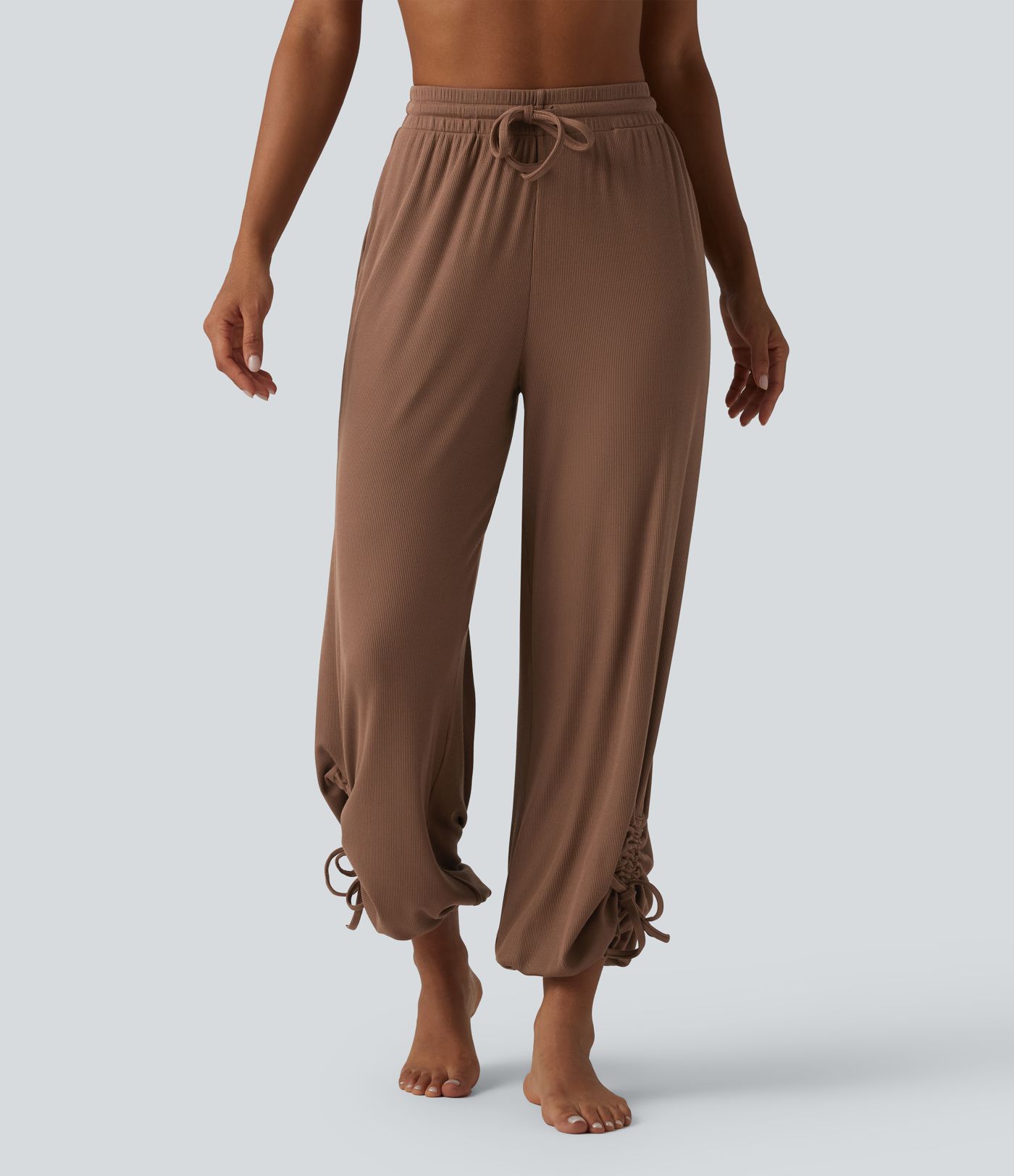 Gathered yoga joggers made from highly elastic ribbed knit with a high waistband, side pockets and drawstring.