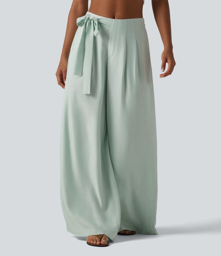 Aukšto liemens, šone surišamomis raišteliais ir laisvo audinio kelnės su kišenėmis