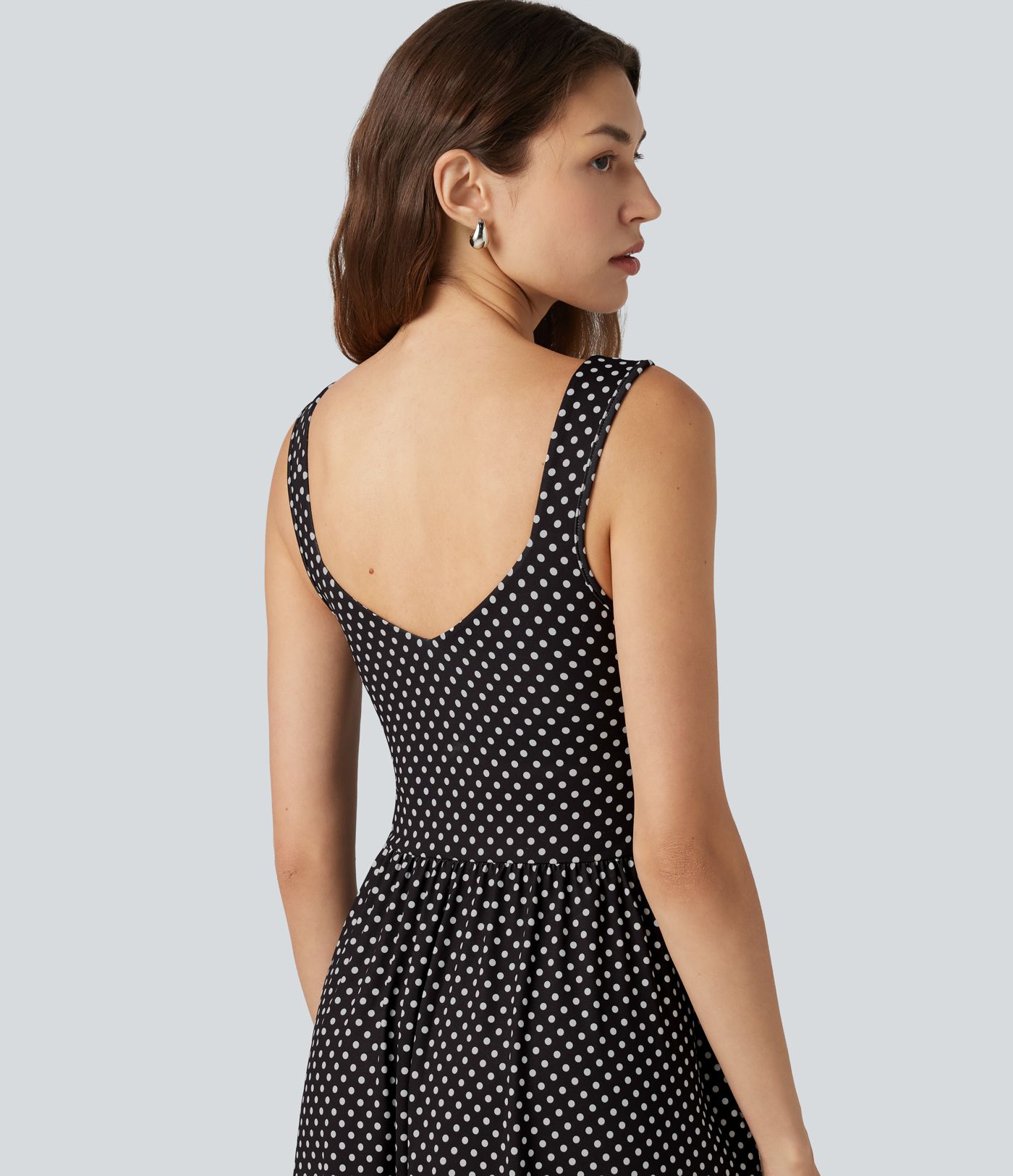 Robe midi fluide et décontractée à pois, sans manches, dos-nu et croisée, avec poches.
