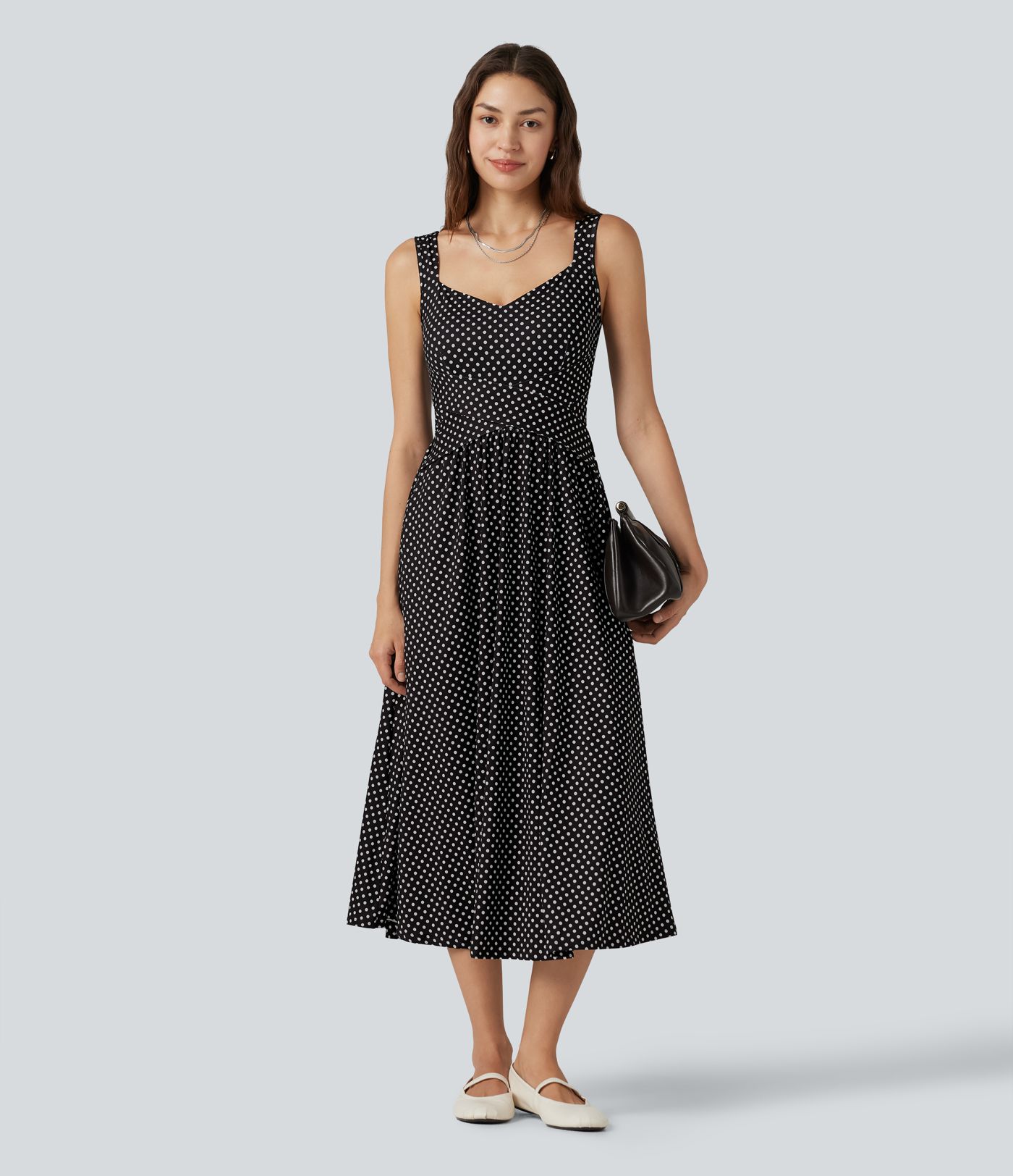 Robe midi fluide et décontractée à pois, sans manches, dos-nu et croisée, avec poches.